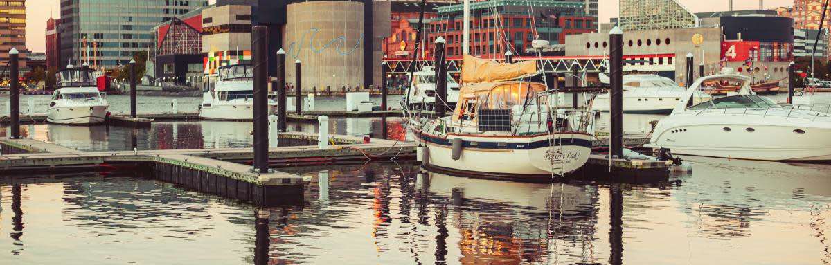 Boats along dock by city skyline in Baltimore, Maryland.